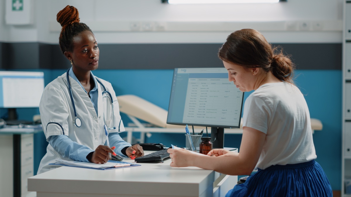 Arzt reicht Patientin Medikamente und Rezept bei Konsultation