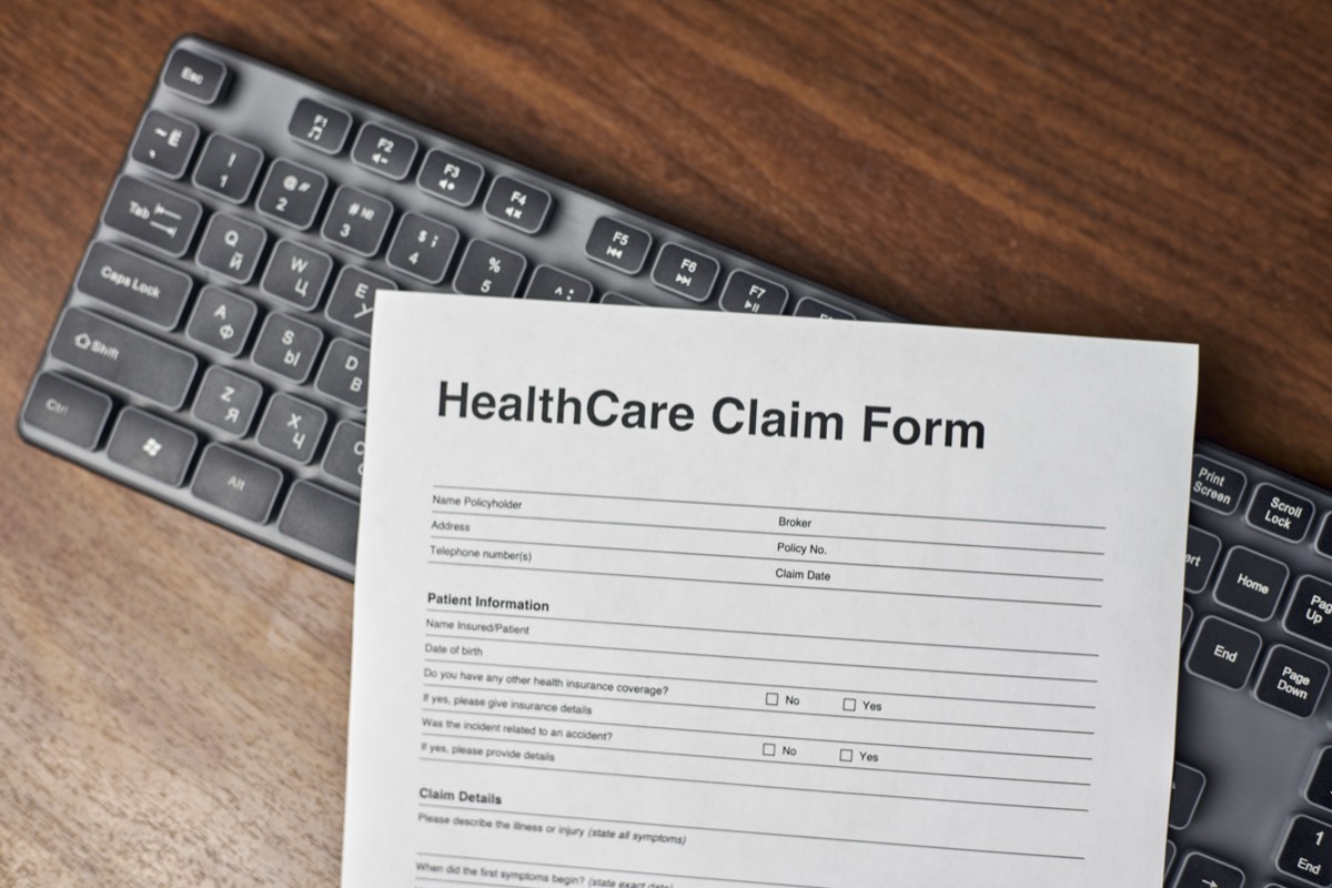 HealthCare Claim Form auf Tastatur auf Holztisch – Arztrechnung bei der Krankenkasse einreichen