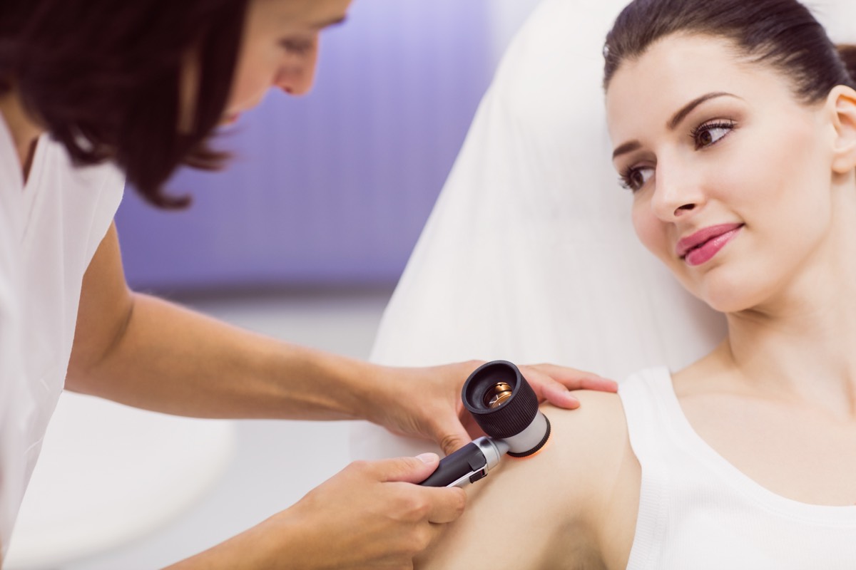 Dermatologin untersucht Haut einer Patientin mit Dermatoskop – Hautdiagnose beim Arzt