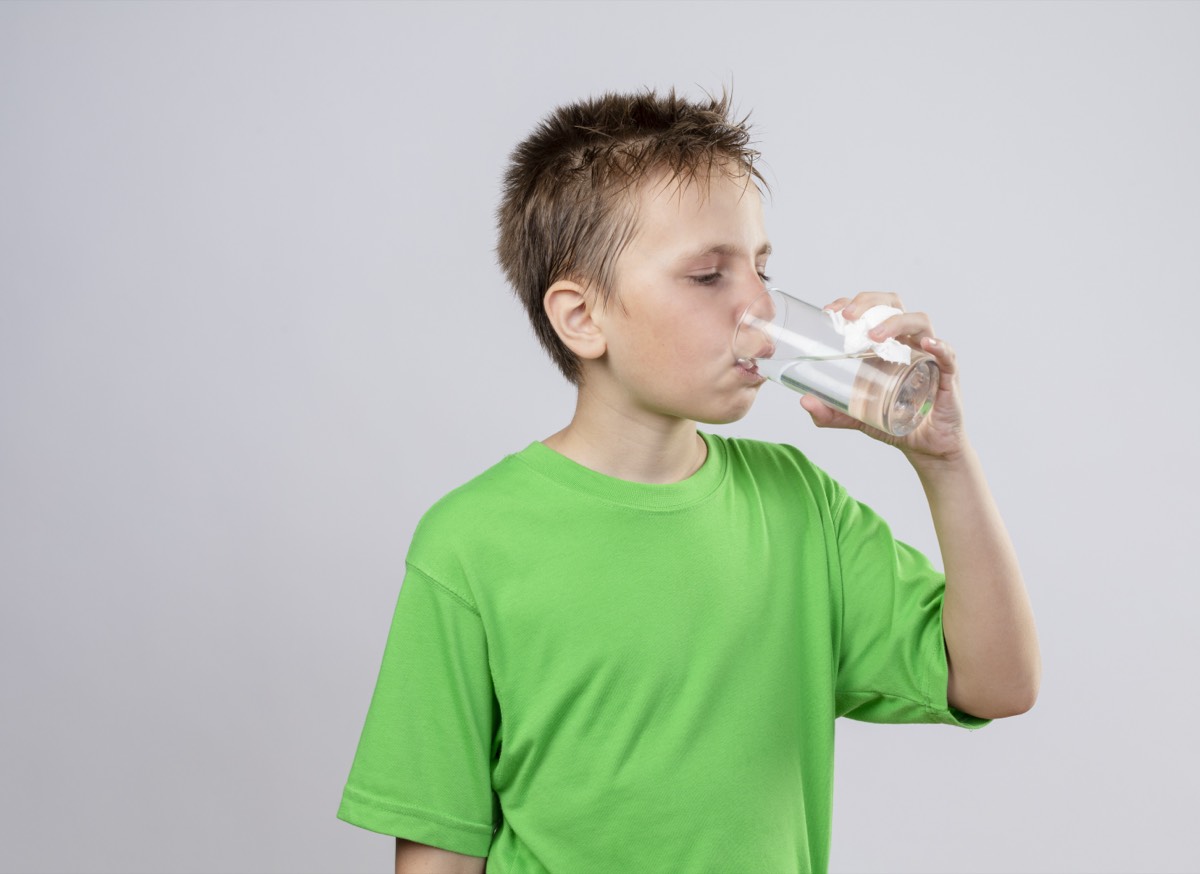 Kranker Junge trinkt Wasser aus einem Glas – Flüssigkeit und Elektrolytlösung bei Durchfall