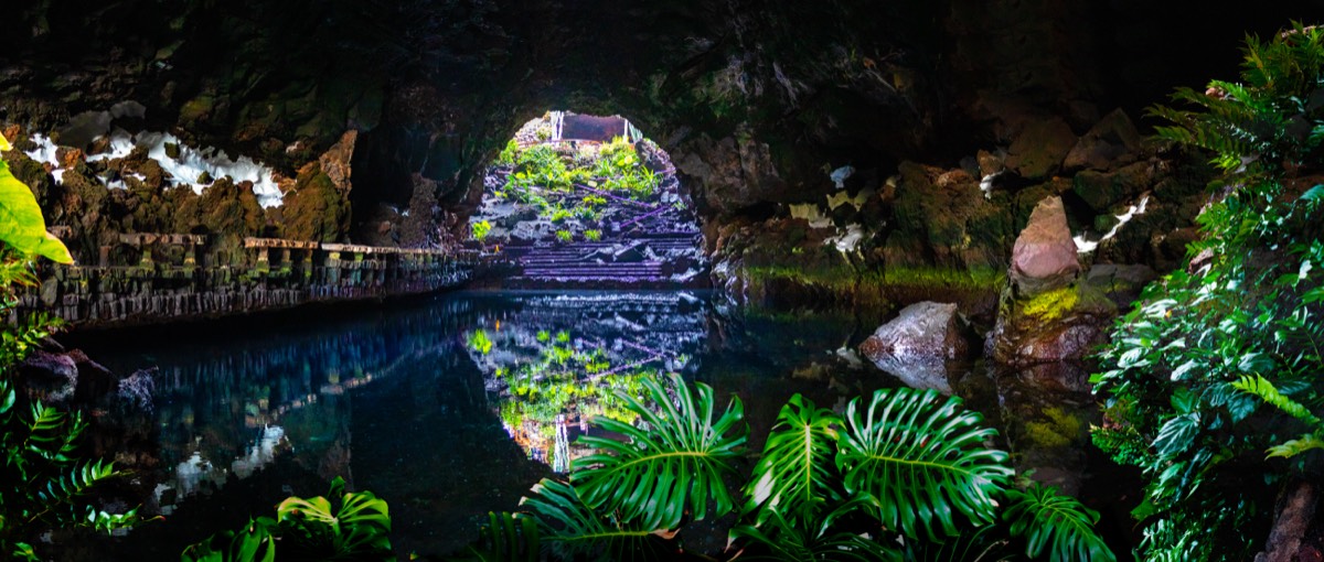 Blick in die erleuchtete Lavahöhle der Jameos del Agua auf Lanzarote – ruhiger unterirdischer See mit Spiegelung