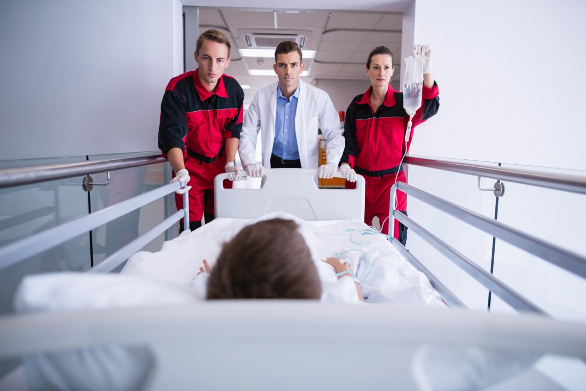 Sanitäter und Arzt transportieren Patienten auf Trage durch Krankenhausflur