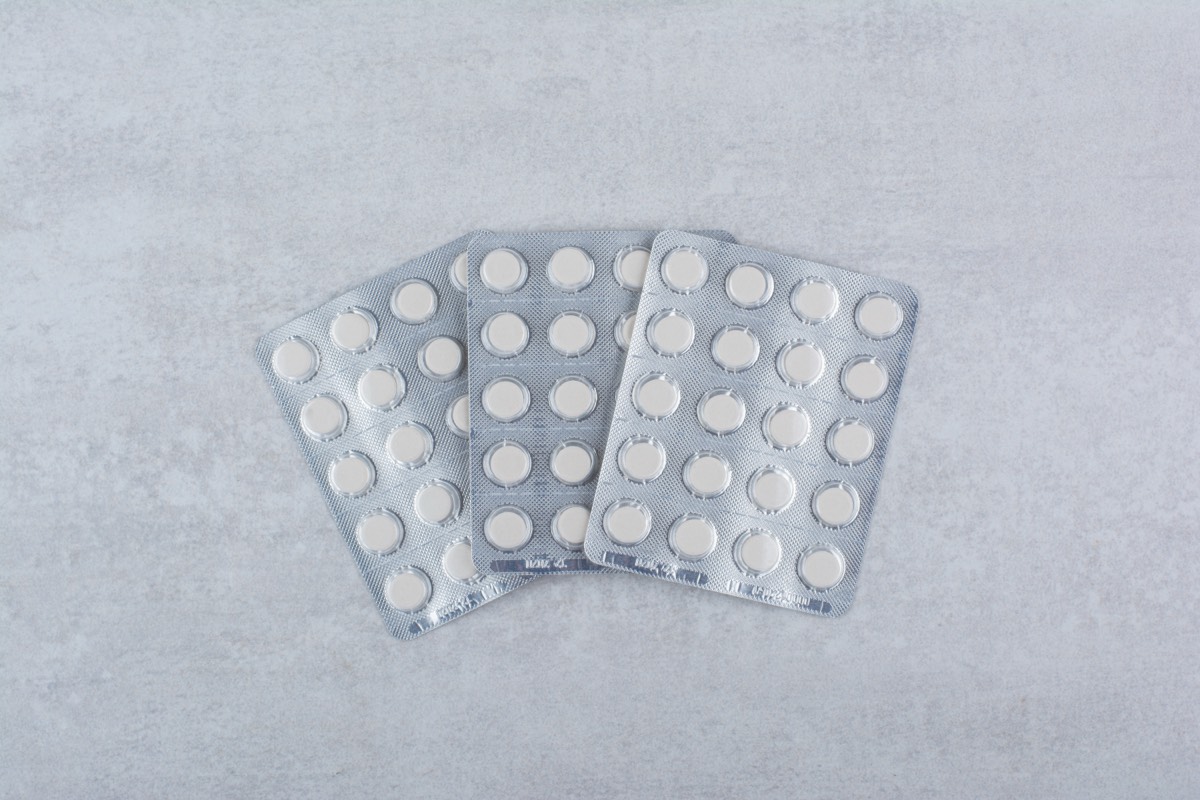 Drei silberne Blisterpackungen mit runden weißen Tabletten auf grauem Marmor-Untergrund