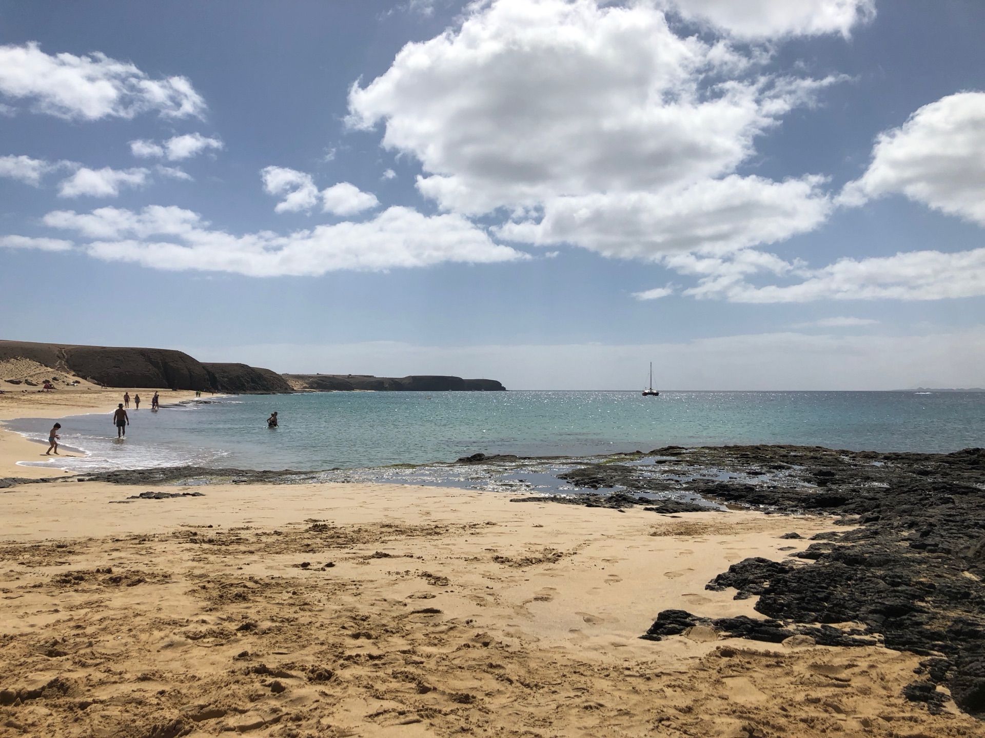 Playa de Papagayo auf Lanzarote – goldener Sandstrand mit türkisem Wasser, schwarzen Lavafelsen und Segelboot