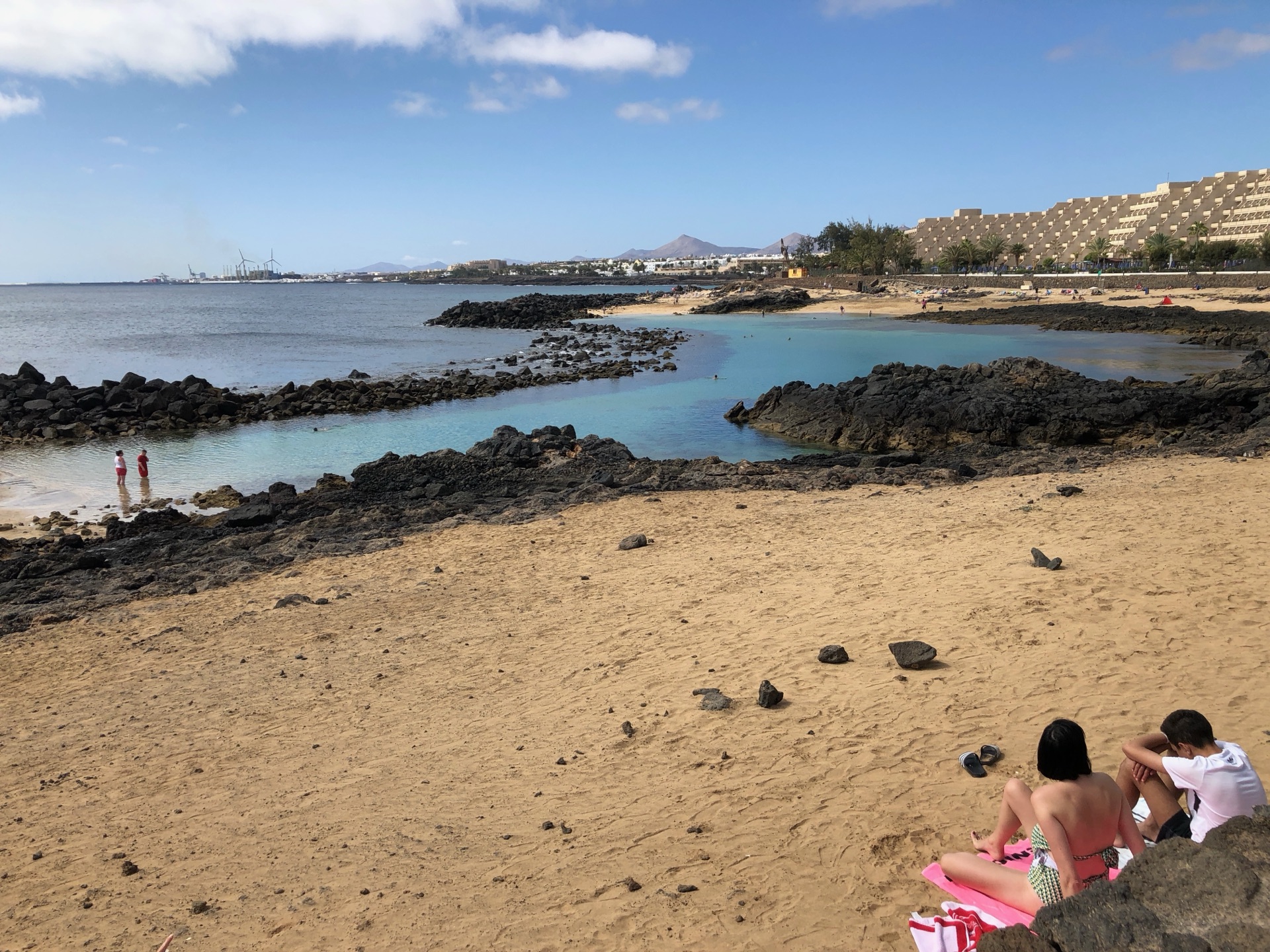 Strand Costa Teguise Lanzarote – weißer Sandstrand mit türkisem Wasser und Lavafelsen im Hintergrund