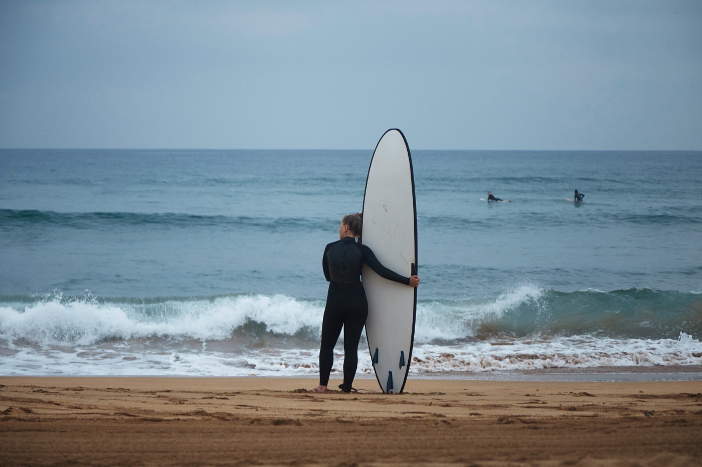 Surfer auf einer Welle an der Playa de Famara auf Lanzarote mit den Famara-Klippen im Hintergrund