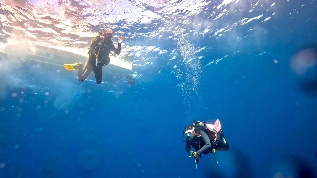 Zwei Taucher im kristallklaren Atlantik vor Lanzarote – Blick von unten aufs Boot