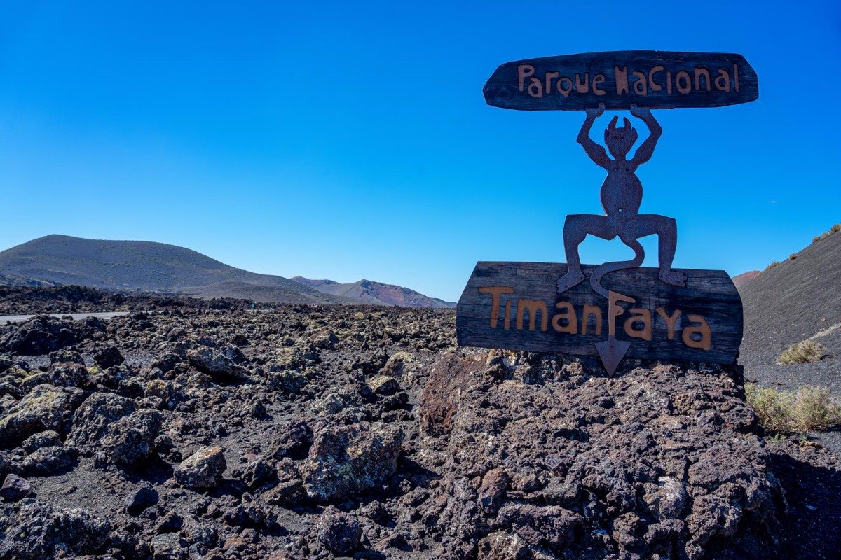 Blick auf die schwarze Vulkanlandschaft des Timanfaya Nationalparks auf Lanzarote – karge Lava-Felder unter blauem Himmel