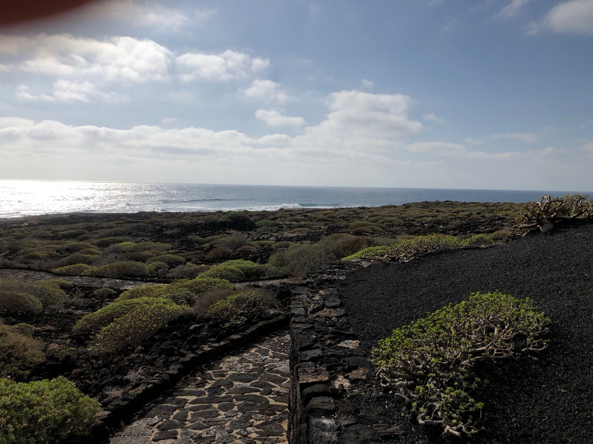 Wanderweg entlang der Vulkanküste Lanzarotes – Steinpfad durch schwarze Lavalandschaft mit Meeresblick